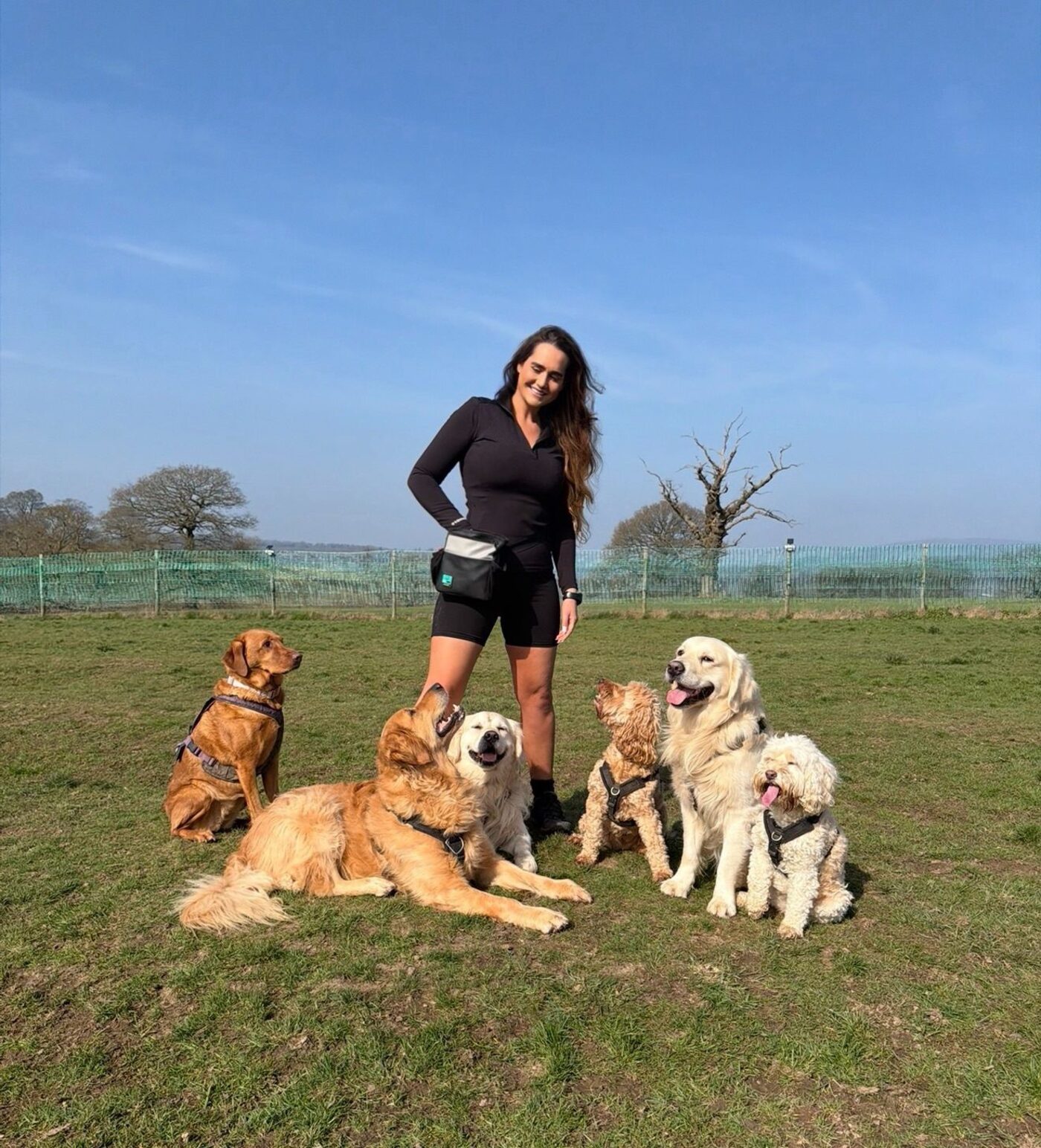 Siobhan, Head Trainer, with a group of happy dogs in a field